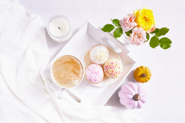 Cup of coffee, pink pumpkins, roses bouquet, cupcakes on the white background. Feminine atmosphere. Woman power. Happy Halloween. Girlish fall composition. Coffee break at home. Holiday girly concept.