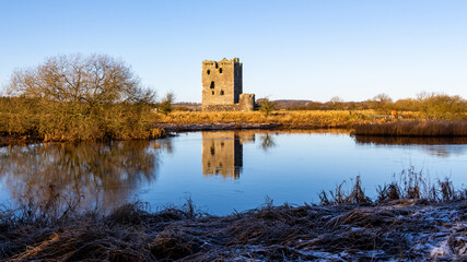 Threave Castle reflecting on the River Dee in the winter sun and ground frost