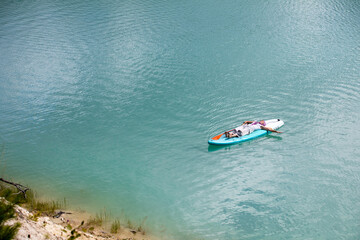The girl is sunbathing on a sapa on a pond with turquoise water