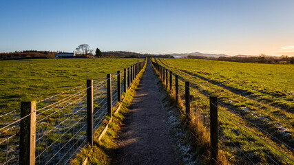 Fototapeta na wymiar A fenced trail through agricultural land in the Scottish countryside in winter