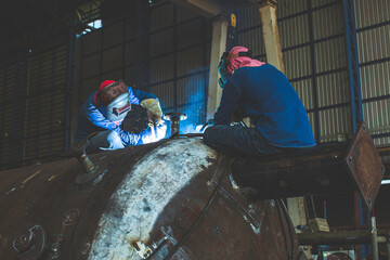 Welding two male worker metal is part in machinery nozzle tank construction