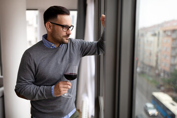 Portrait of handsome young man holding glass of red wine