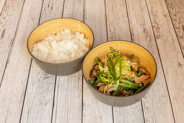 Bowl of filipino bicol of meat with vegetables and garnished with white rice on white table