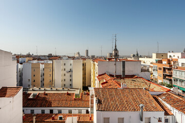 Vista de tejados con tejas de barro, edificios y campanarios de iglesias cristianas en la ciudad de Madrid.