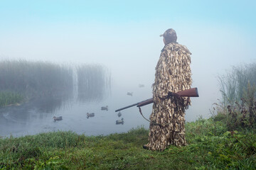 Hunter with a shotgun tracks down ducks on the lake. Duck Hunting.