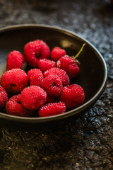 picking Tibetan raspberries in a black bowl on the background