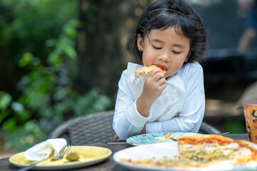 Little girl enjoy eating pizza outdoor.