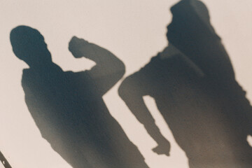 Elbow bumping safety greeting of two people shadow on wall of coronavirus COVID-19 pandemia. New normal.