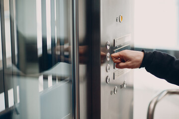 Close up of forefinger pressing the button elevator during coronavirus pandemic covid-19