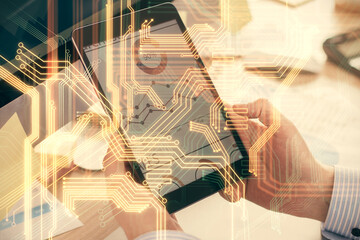 Double exposure of man's hands holding and using a digital device and tech theme hologram drawing. Technology concept.