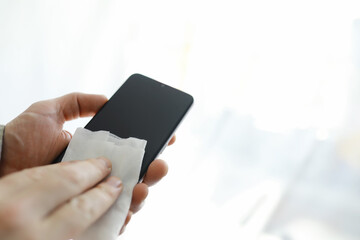 Сleaning concept. Wipe dirt off surfaces. Disinfectant treatment of phone screenl. Sanitary treatment at home quarantine.