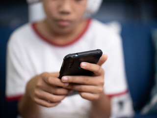 asian boy sit on sofa and using mobile phone in living room at home.