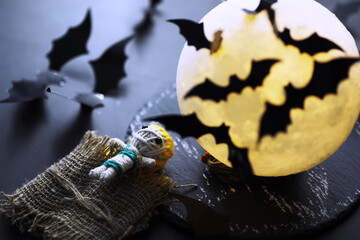 Halloween holiday concept. Old stone table in a shape of bats. Halloween paper decorations on dark background. Moon toy.