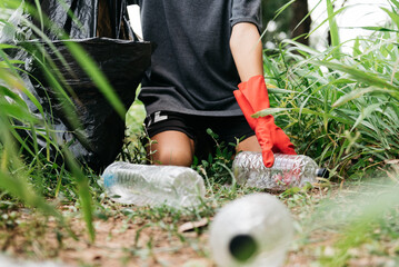 Fototapeta premium Boy man hand pick up plastic bottle in the forest. nature conservation and Environment concept.