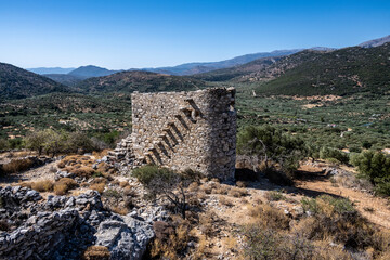 Fototapeta na wymiar ancient stone mills and their ruins on the slopes of the mountains in Crete on a sunny day