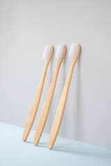 The bamboo toothbrush stands upright. blue surface, gray background. Biodegradable personal care products. No plastic concept. Zero waste.
