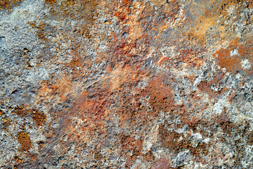 Rough stone surface with spots of rusty red and grey. Colorful texture in old mine