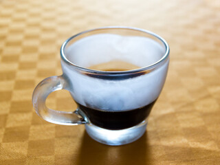 Iced cup of espresso on a table with orange tablecloth