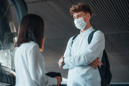 Trabajadores j&oacute;venes con mascarilla esperando el autob&uacute;s para viajar a su destino charlando