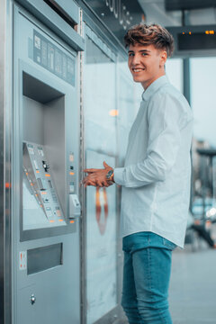 Hombre joven directivo con una sonrisa de entusiasmo consiguiendo su boleto en la estaci&oacute;n del tranv&iacute;a para viajar a su destino