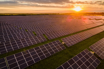Aerial view of large sustainable electrical power plant with many rows of solar panels for...