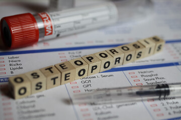 Viersen, Germany - June 1. 2021: Closeup of word osteoporosis on laboratory requisition slip with syringe and vial