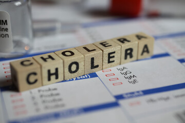 Viersen, Germany - June 1. 2021: Closeup of word cholera on laboratory requisition slip with syringe and vial