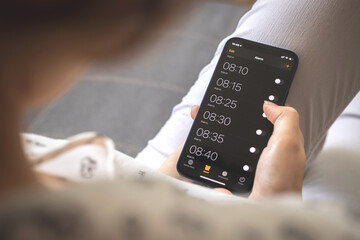 Alarm on mobile phone for morning wake up, mobile screen with alarm clocks close-up