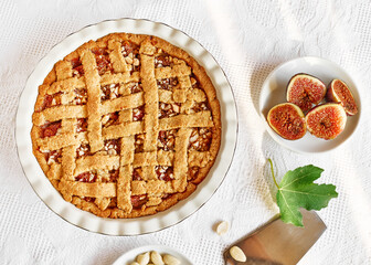 Homemade fig tart with cookie crust base. Shortbread pie with figs and almond on the table with white tablecloth. Autumn baking. Top view.
