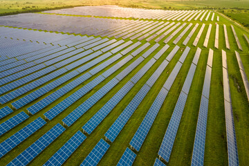 Aerial view of large sustainable electrical power plant with many rows of solar panels for producing clean ecological electric energy in morning. Renewable electricity with zero emission concept.