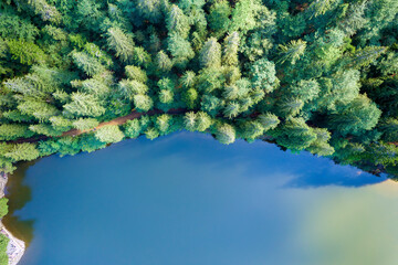 Top down aerial view of big lake with clear blue water between high mountain hills covered with...