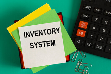 INVENTORY SYSTEM - words on note paper against the background of a calculator and paper clips.