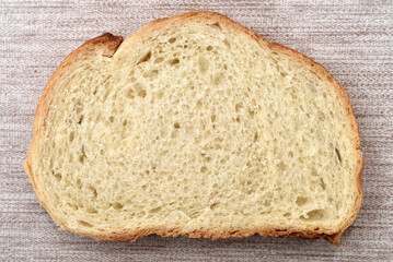 Slice of fresh homemade white bread on the rustic wooden table. Close-up. Top view.