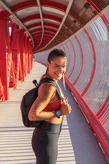 Chica deportista con expresión feliz, con la mochila para entrenar.