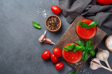 Tomato juice, spices, basil, salt and garlic on a gray-blue background. Top view, copy space.