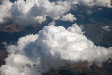 Aerial view from airplane window of white puffy clouds on bright sunny day.