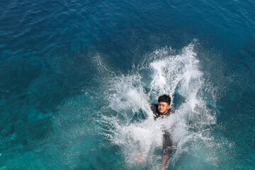 A man jumping into the sea splashing the water