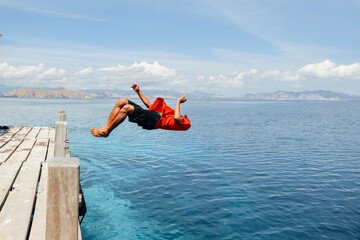 A man doing backflip into the sea water