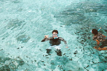 Happy asian man in snorkeling mask posing on the transparent sea water