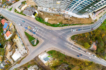 Top down aerial view of busy street intersection with moving cars traffic.
