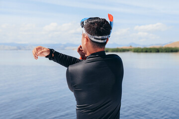 Man in wetsuit does warming before snorkeling on the sea