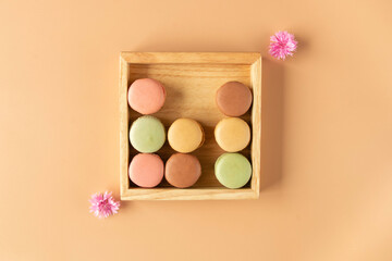 French colorful macaroons in a wooden box on a soft beige background 