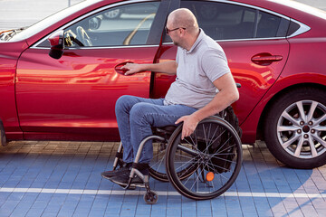 Fototapeta na wymiar Young handicapped driver getting in red car fom wheelchair