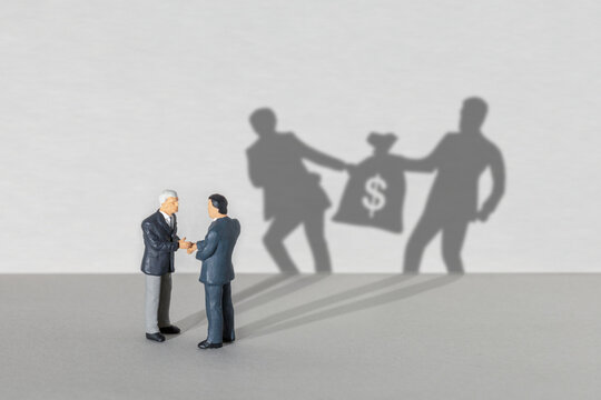 Profit sharing. Two businessmen in suits are shaking hands. SHADOW two businessmen take a bag of money from each other