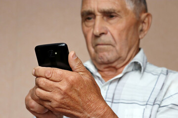 Elderly man using mobile phone, looking on smartphone screen. Concept of online communication in retirement, sms, reading news