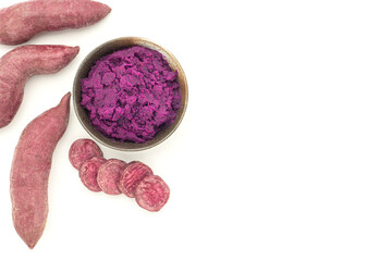 Purple yams pile and mashed potatoes on a dish isolated on white background with copy space for text. Purple sweet potatoes. Top view. Vegan fruit and healthy fruits concept