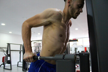 Naklejka premium young muscular caucasian guy training triceps exercise in gym