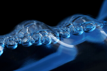 Bubbling cleaning liquid in a transparent bottle on a black background. Abstraction. The concept of...