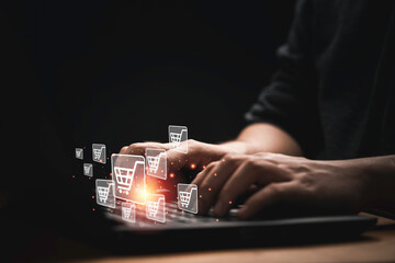 Businessman using computer laptop with shopping trolley cart icon for input order for online shopping concept.