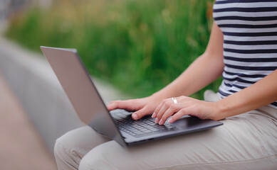 Naklejka premium woman working with laptop in modern university campus park.